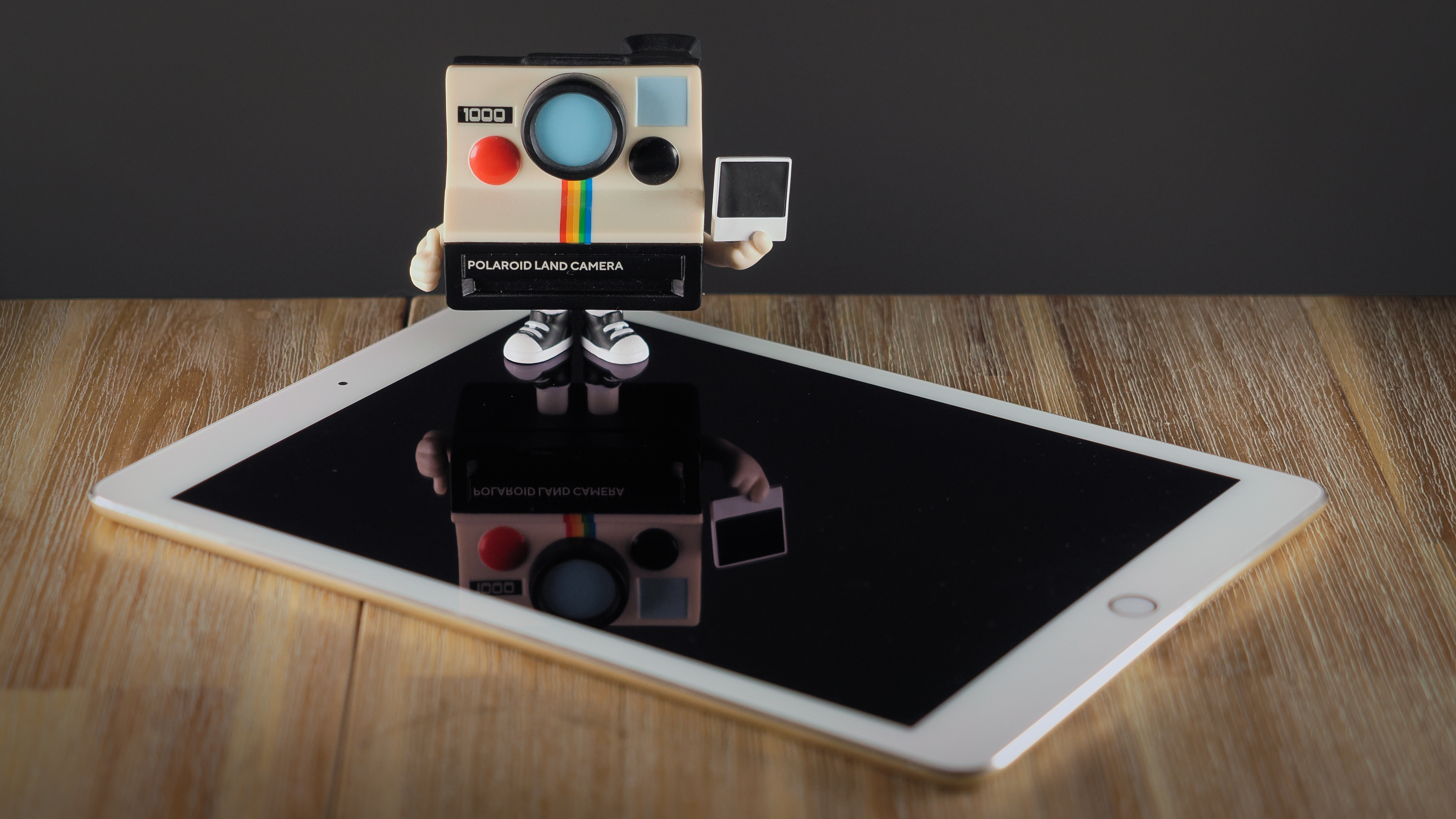 A Polaroid Funki Pop! standing on top of an iPad Air 2 on a wooden surface