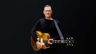 Bryan Adams holding a guitar (studio portrait)