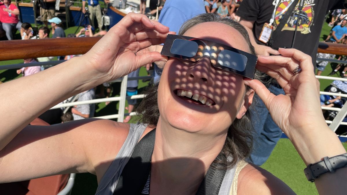 a woman gazes at a solar eclipse through special eclipse glasses