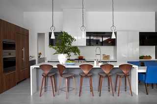 A kitchen island with five counter stools that have a footrest and a wide back