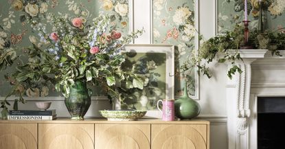 cut flowers in vases in front of floral wallpaper