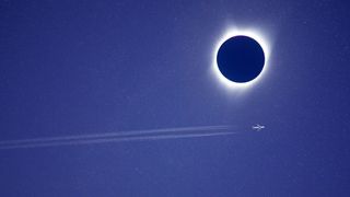 Passenger jet passing across total solar eclipse .