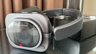 Nothing Headphone (1) Pro with the case on a shiny black and glass table, held in a hand