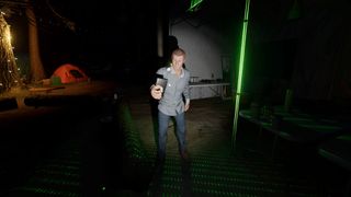 Phasmophobia player holding the spirit box at Camp Woodwind, near the campfire and kitchen area.