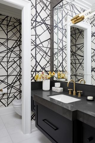 A small bathroom with a wallpaper and a large mirror