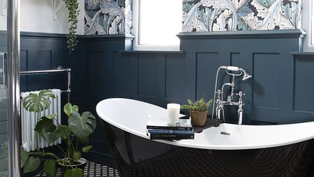 dark bathroom with a black roll top bath and panelled walls