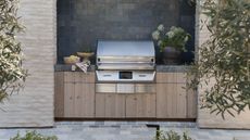 Wooden outdoor kitchen with steel cooker and dark tiles behind