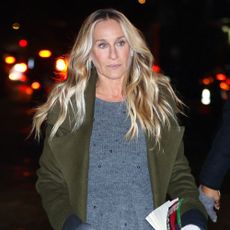 Sarah Jessica Parker walks down the street in New York wearing a polka dot skirt, grey jumper, green jacket and t-bar flats.