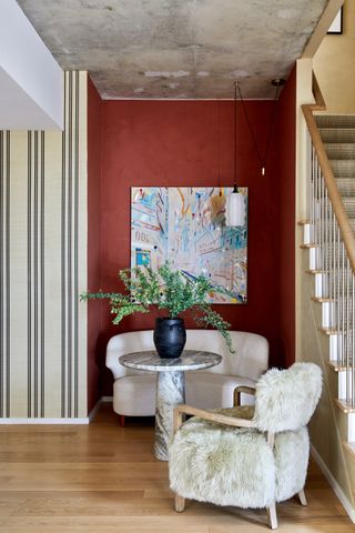 a foyer with burnt orange/red accent wall and striped cream wallpaper