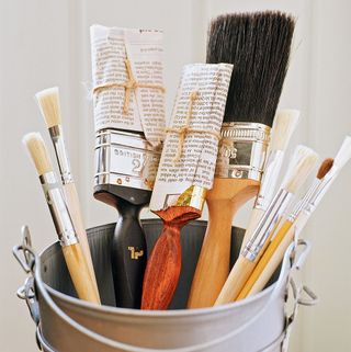 wooden paint brushes in bucket