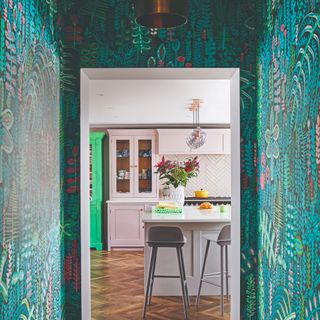 A botanical-print wallpaper covering the whole of a narrow hallway leading into a kitchen