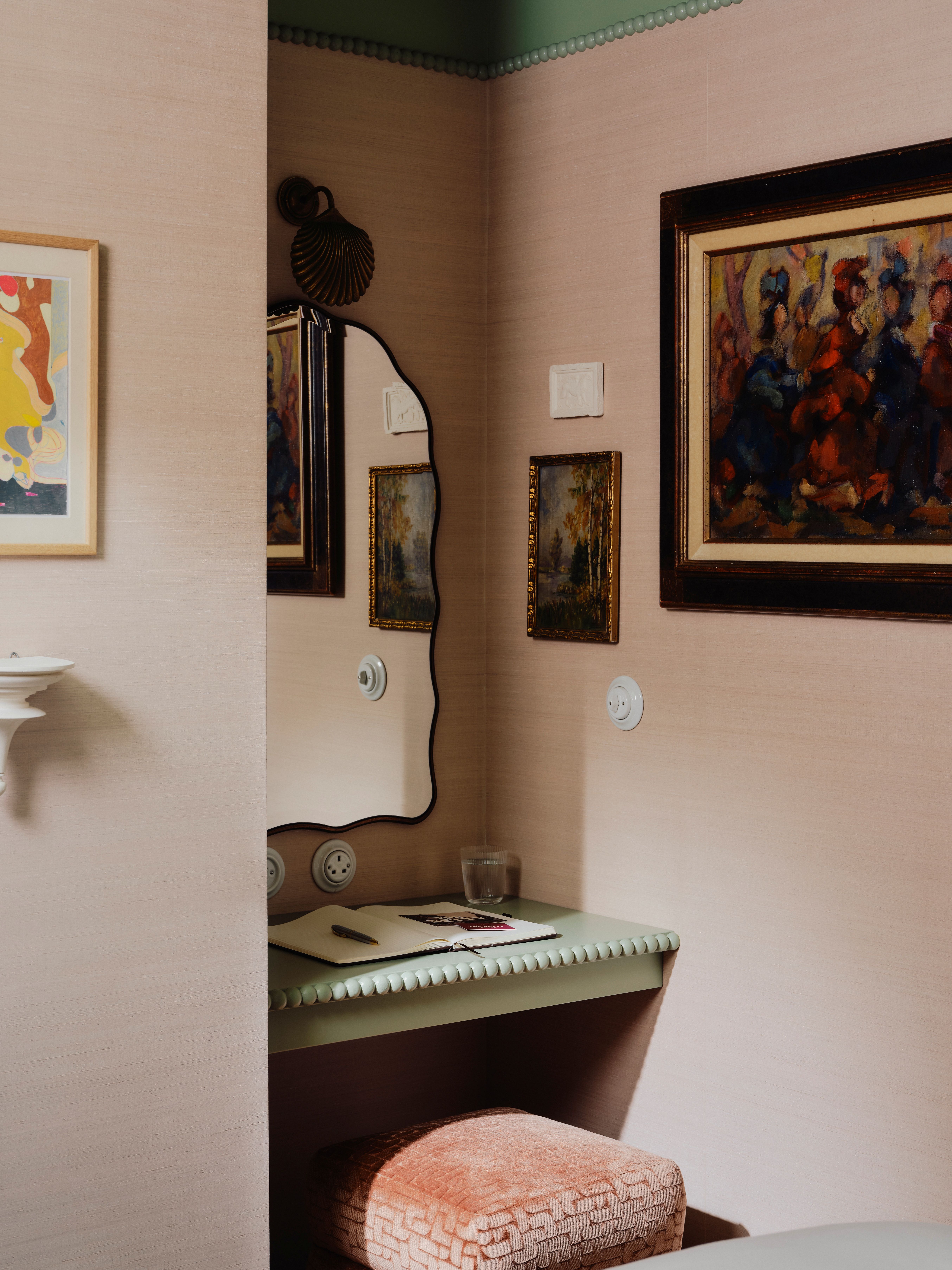 A maximalist hotel room wrapped in patterned tapestries, eclectic framed artworks, velvety surfaces, colorful tiles, and contrasting motifs spanning the hues of green, blue, red, cream, and bordeaux.