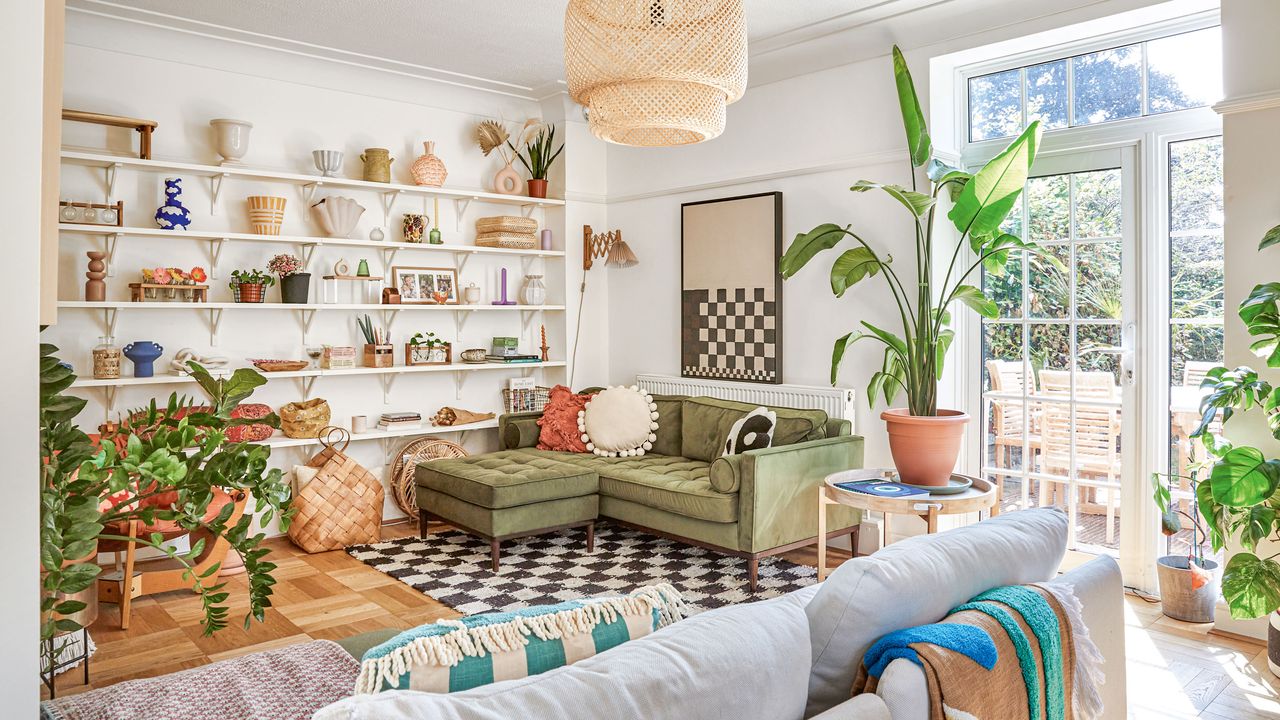 Living room with open shelving, pot plants and green corner sofa