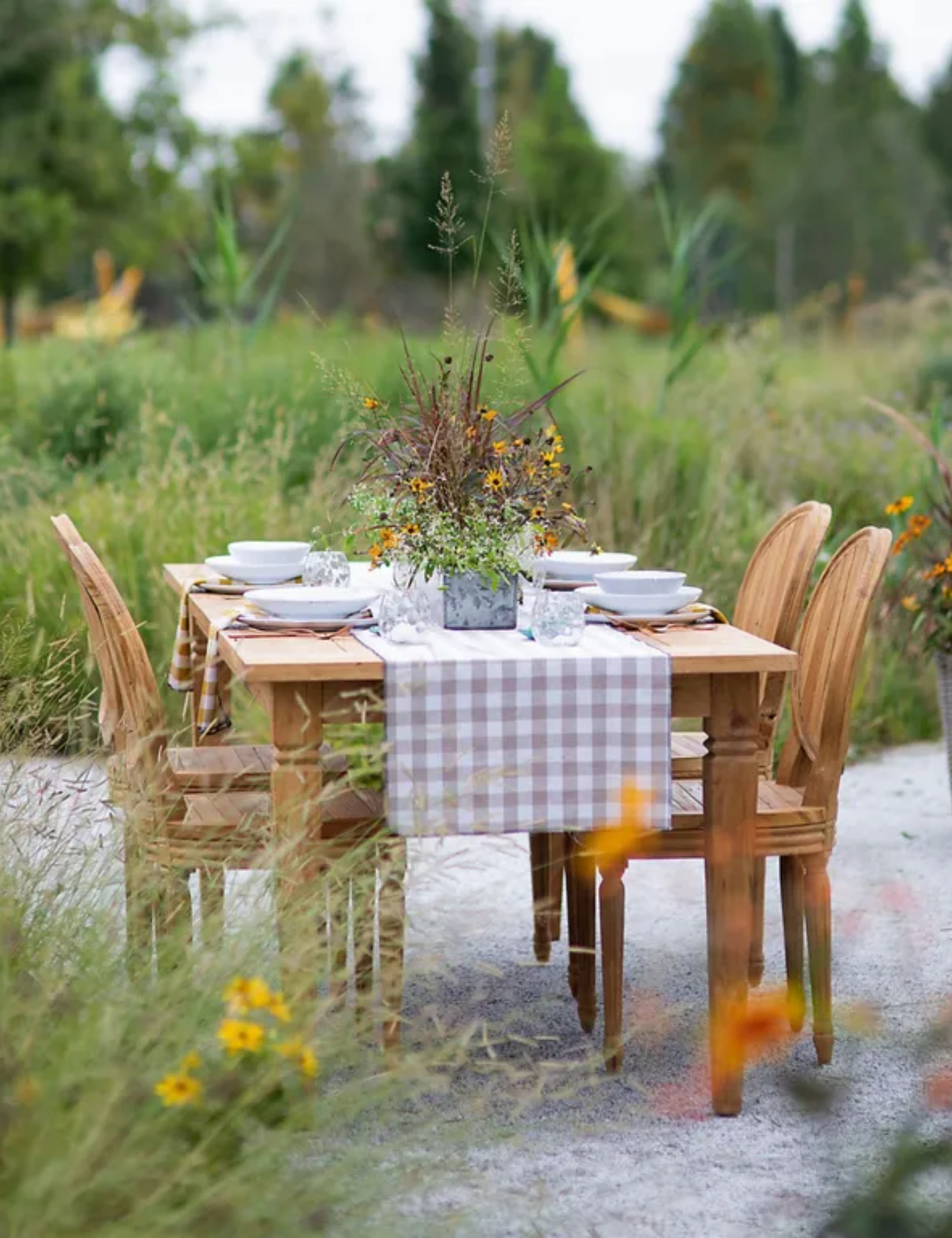 A Reclaimed Teak Dining Table with four teak Palladio chairs, laid for dinner