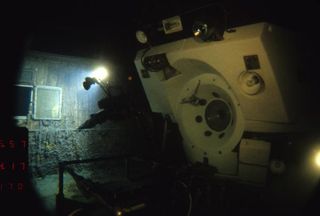 Alvin on deck of Titanic with light shining on bulkhead porthole. Image taken by cameras on the ROV Jason Jr.