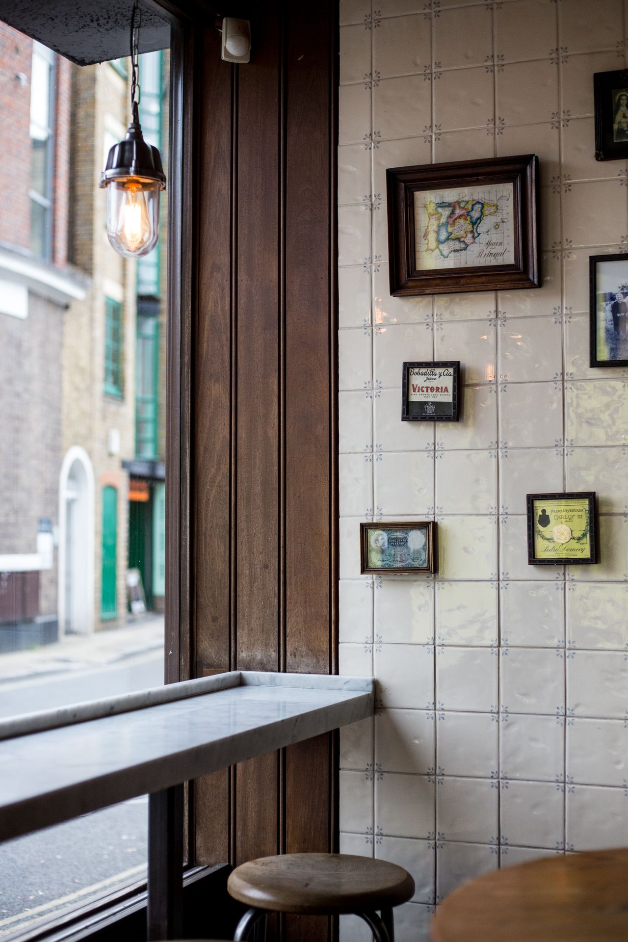 The rustic interior of a restaurant features Spanish white glazed tiles, wooden and leathery surfaces, and marble countertops.