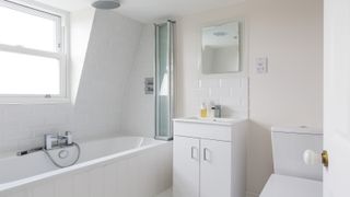 Bathroom with dormer window and fixture like bath and cabinet