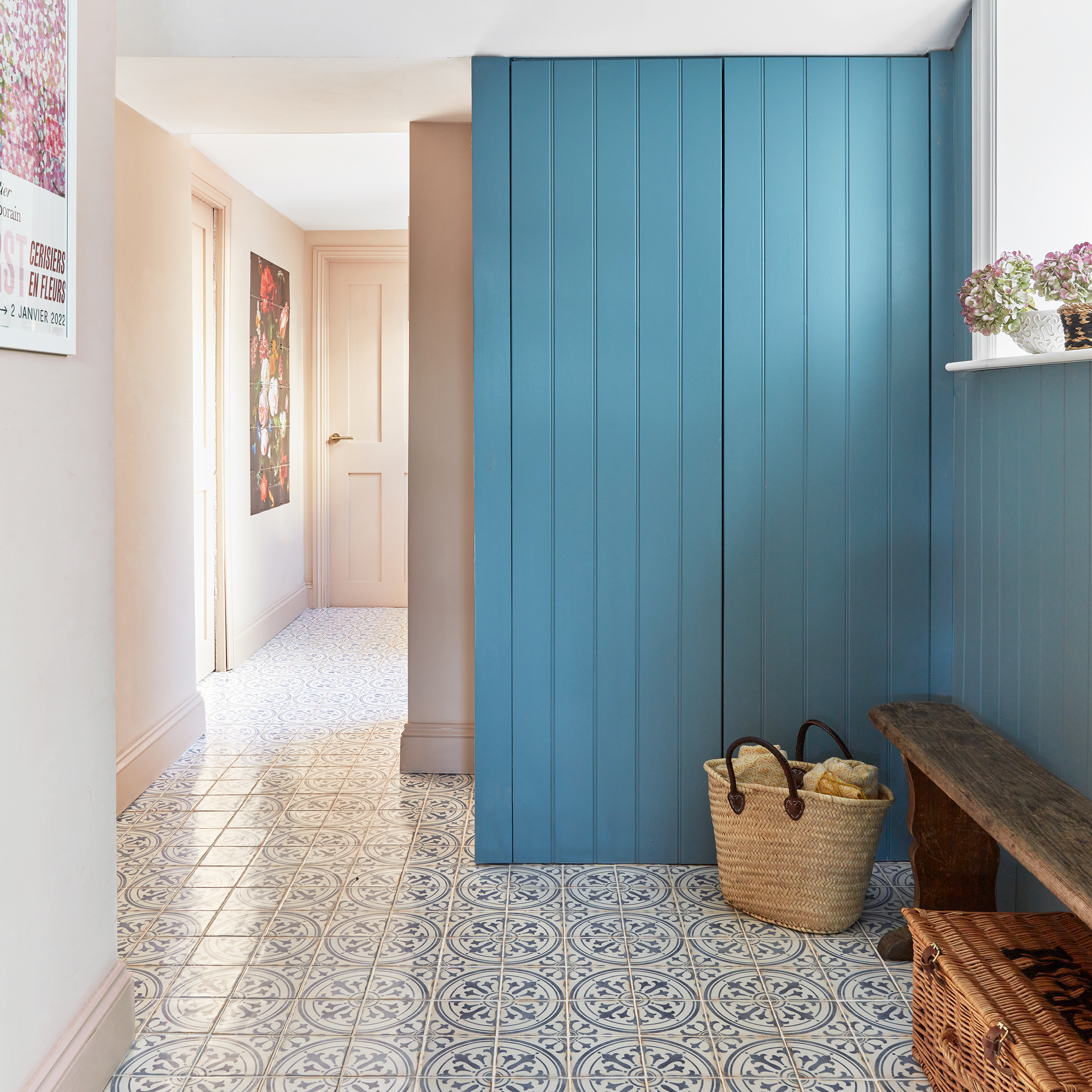 a hallway with patterned floor tiles and a teal blue painted storage cupboards with matching panelling on the wall