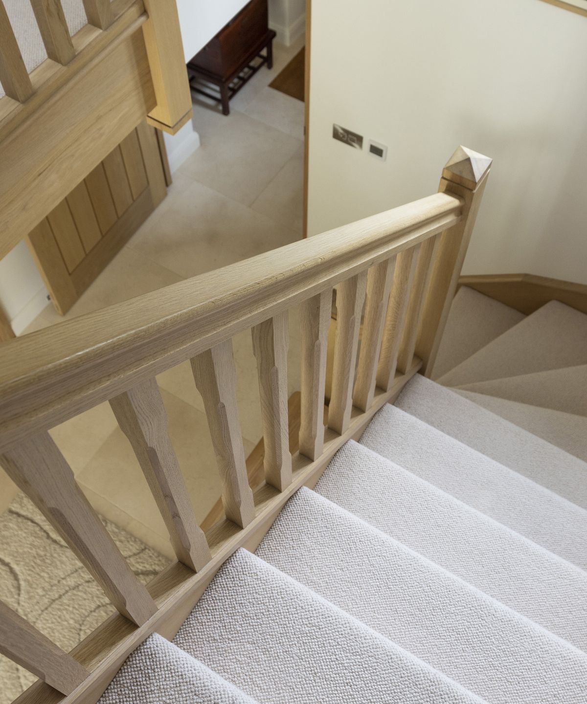 A staircase going with light coloured carpets and neutral timber rails