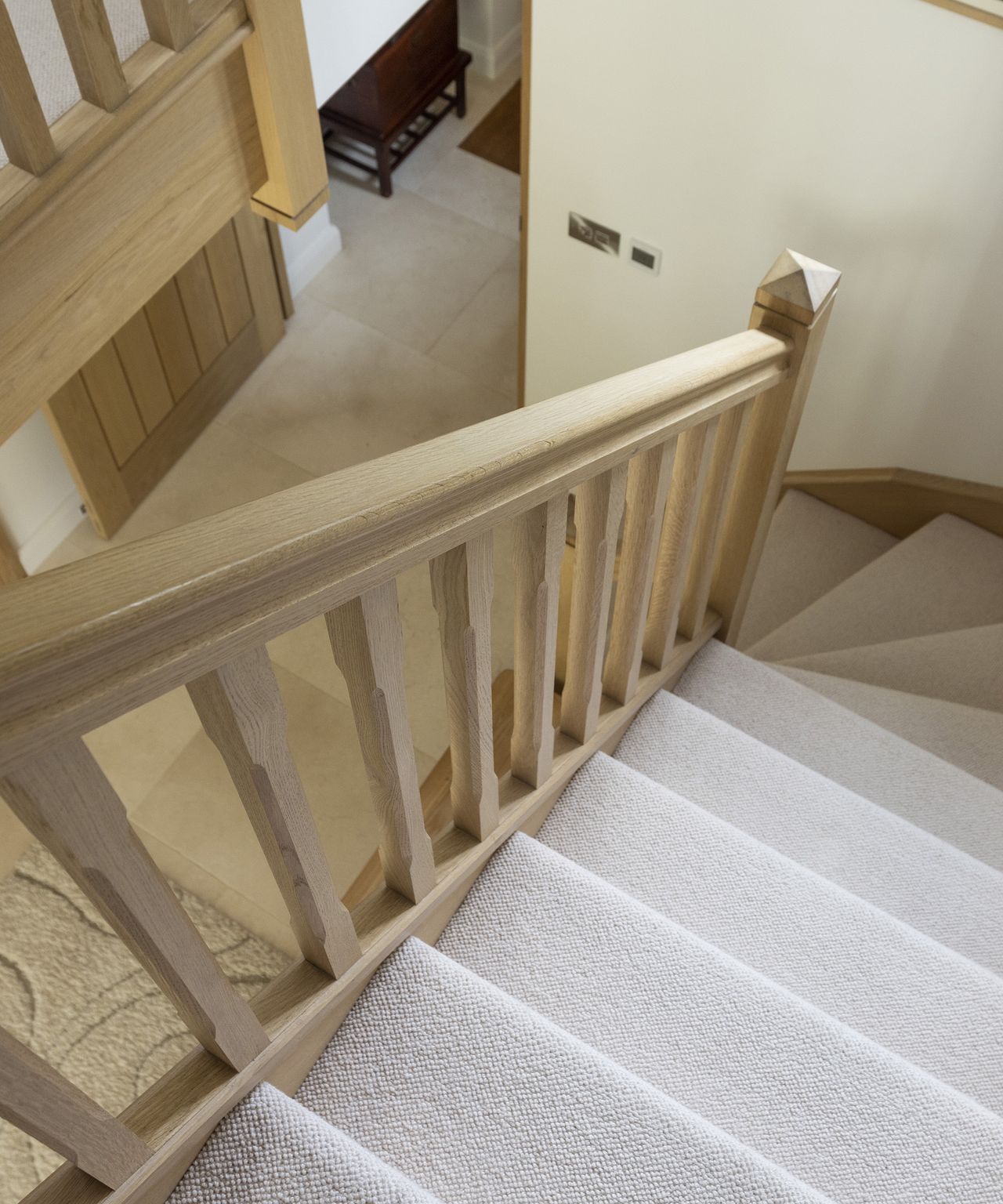 A staircase going with light coloured carpets and neutral timber rails