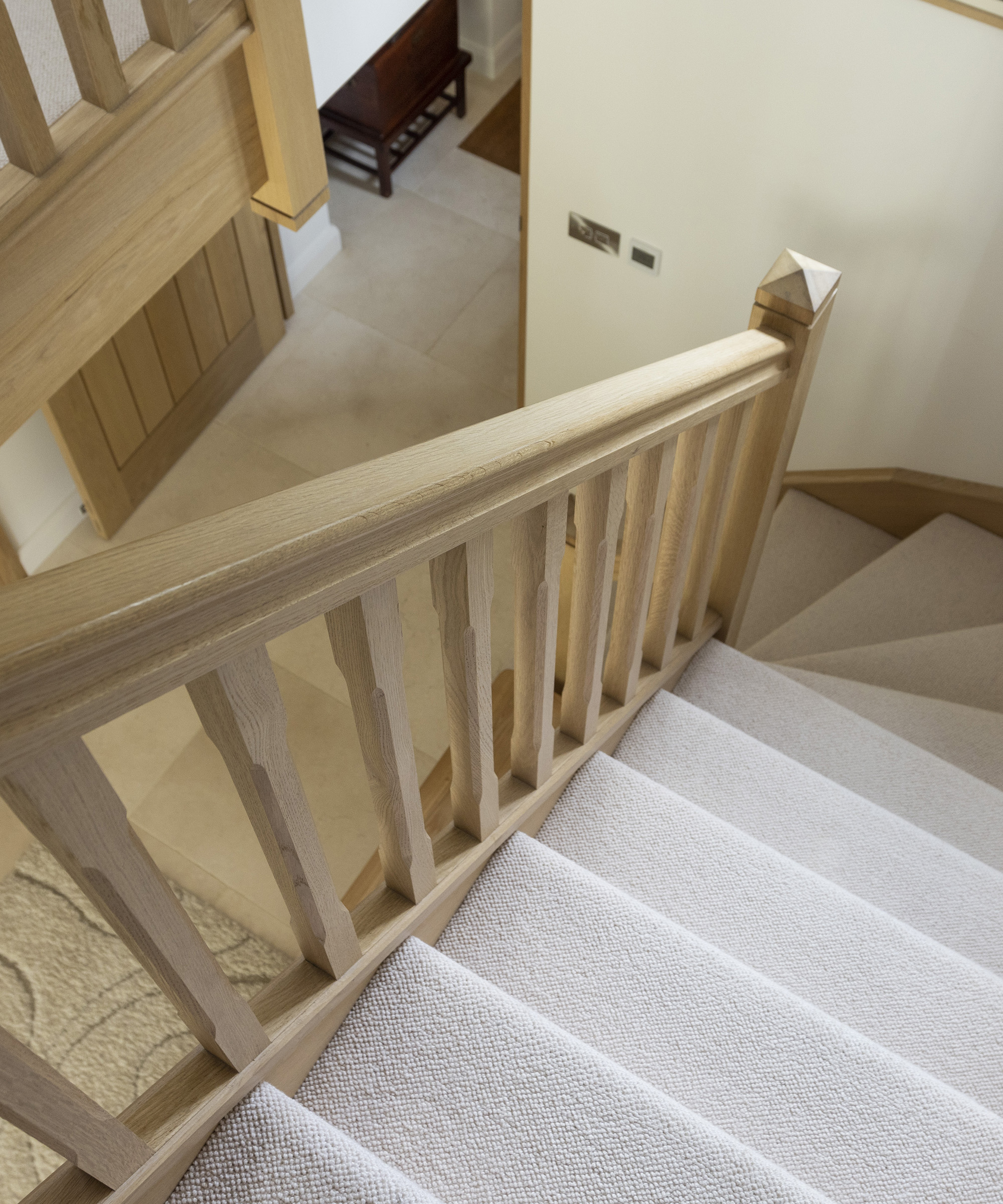 A staircase going with light coloured carpets and neutral timber rails