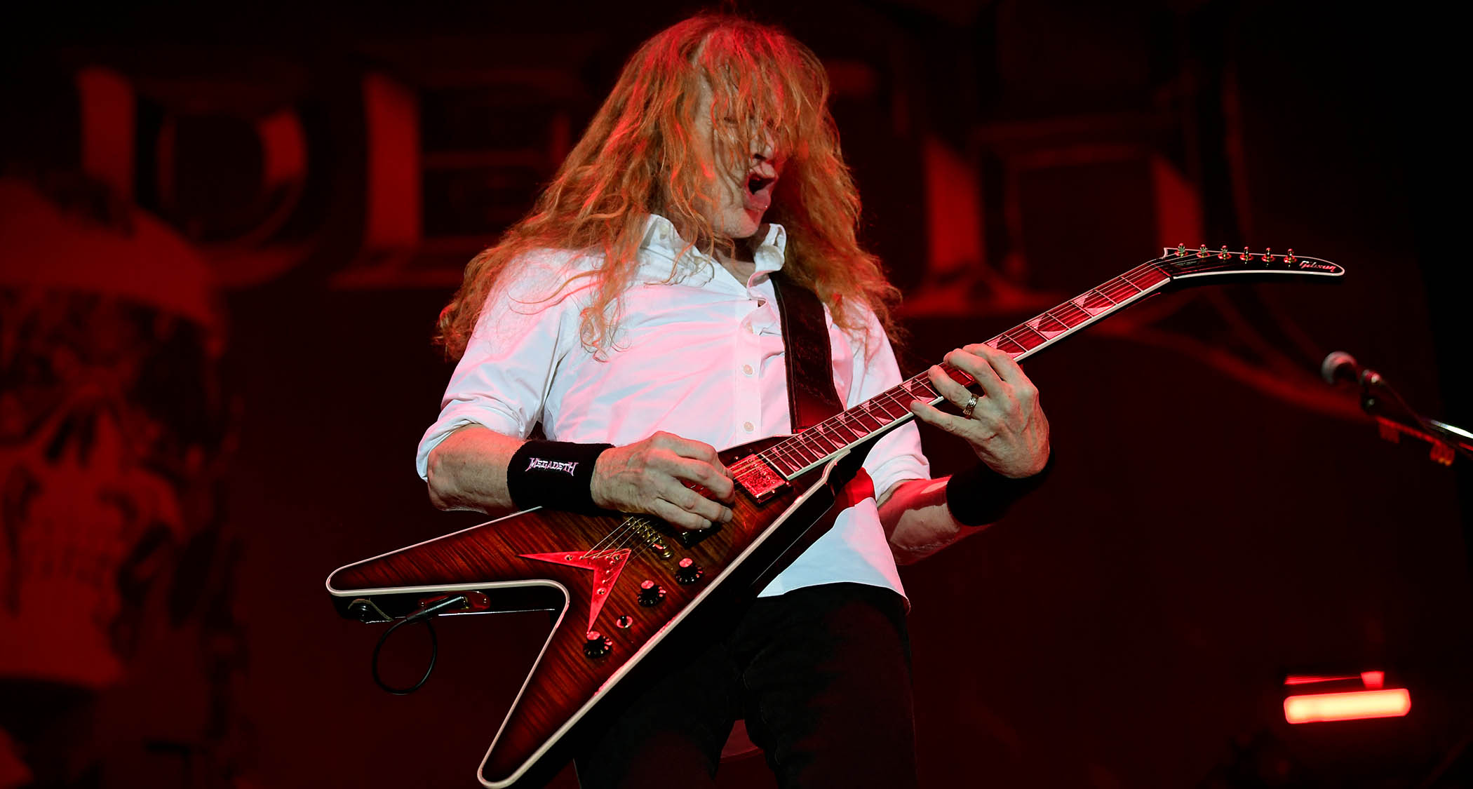 Dave Mustaine wears a white shirt and plays his signature Gibson as he performs with Megadeth in 2025.