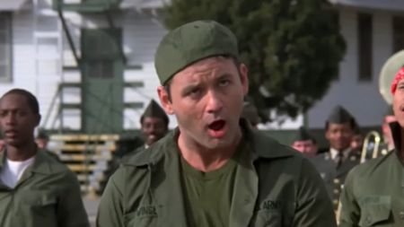 Bill Murray making a funny face in army fatigues and a backwards cap in Stripes. 