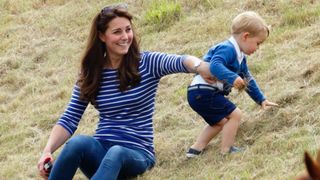 Kate Middleton sitting on a grass verge with a baby Prince George
