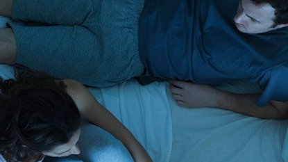 Couple Sitting on Bed Unhappy