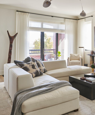 A neutral living room with large windows and a white sofa