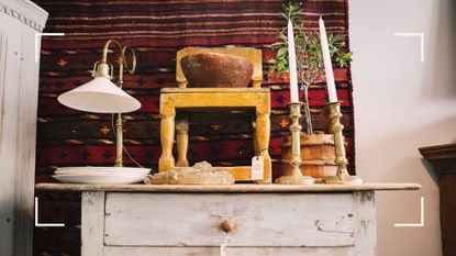 Vintage cream painted table with chair stacked on top and brass candlesticks piled up to support a guide for avoiding common mistakes when buying second hand furniture