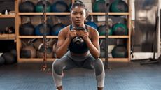 Woman doing a kettlebell squat in a gym