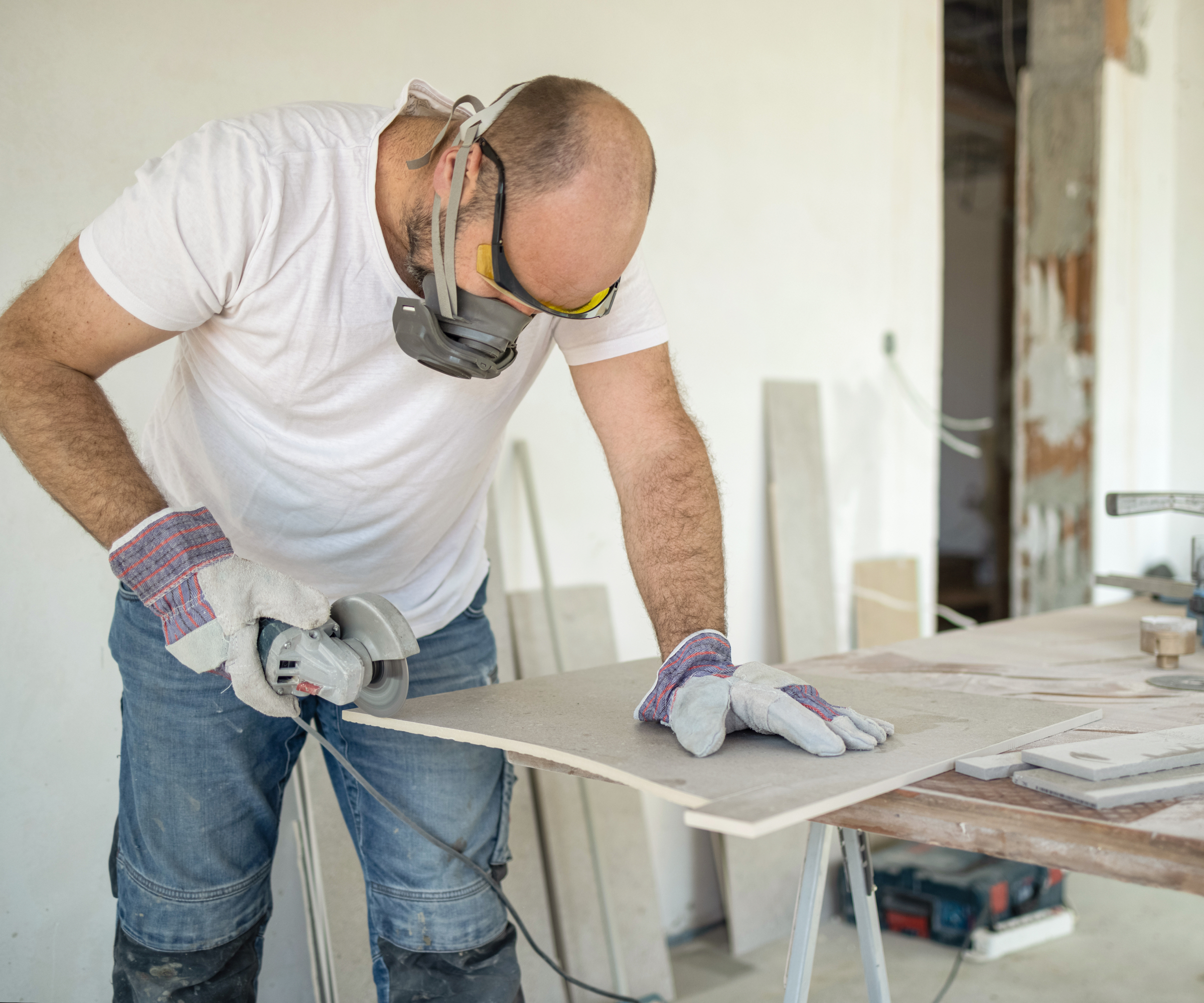 male wearing PPE cutting plasterboard with power toos