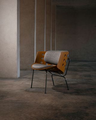 Wooden backed chair with metal legs and grey cushioning in a concrete room