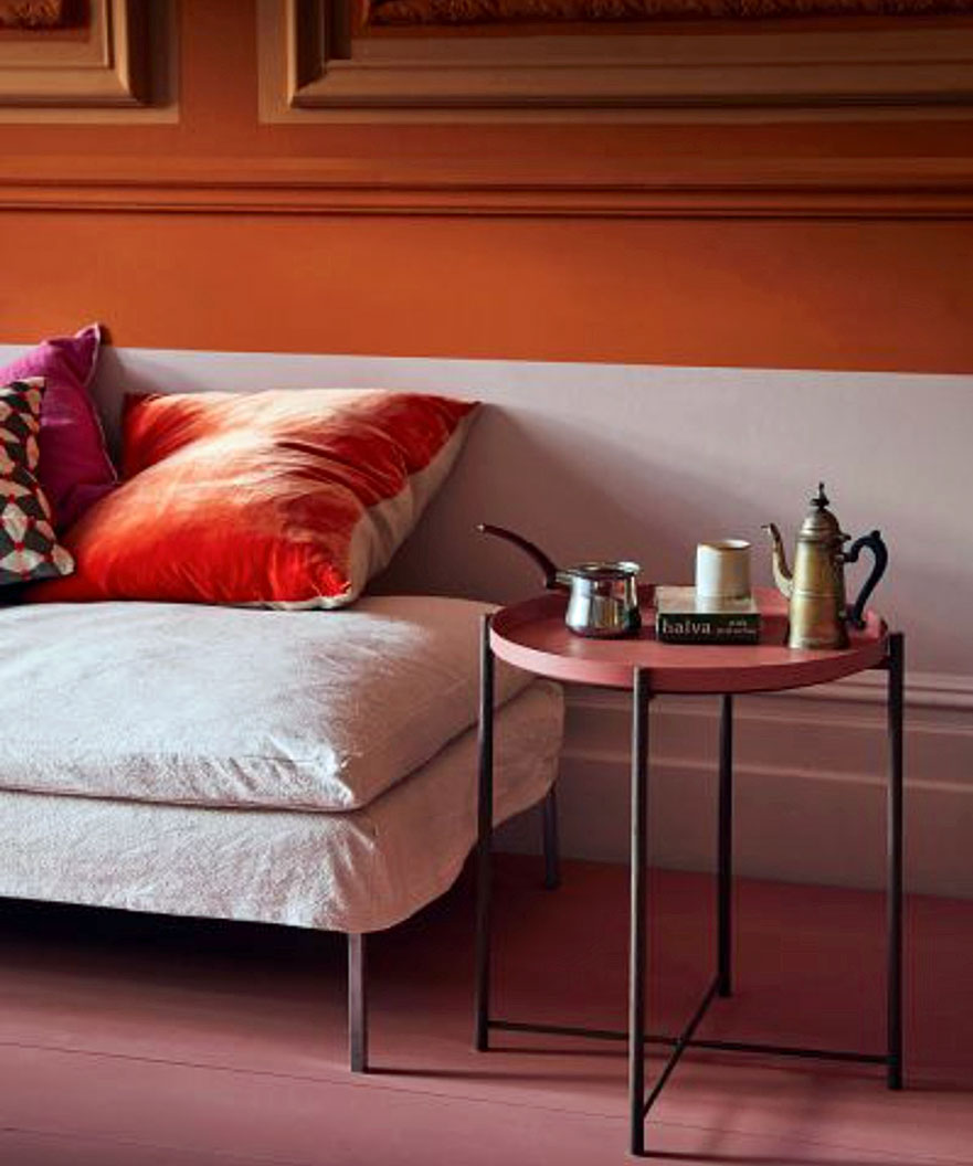 Living room color schemes in hot orange and salmon shades, with two-tone walls and a metal side table.