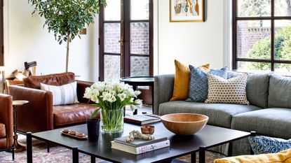 living room with cream walls, windows,, grey sofa, leather accent chairs, black rectangle coffee table