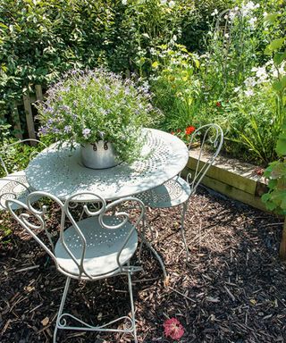 patio made with bark chippings with a circular bistro set in a small garden