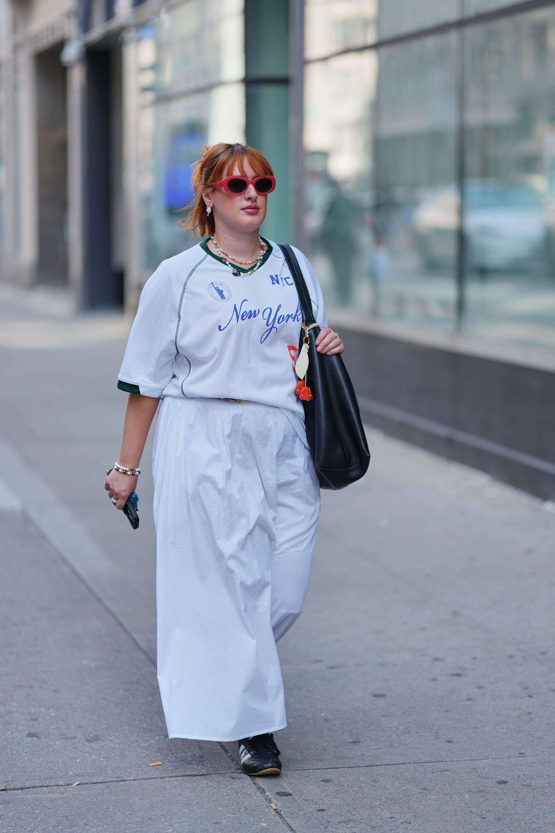 A woman wears a white top, white pants, and Adidas sneakers.