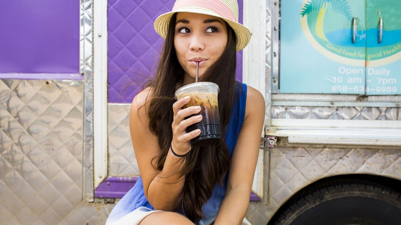 A girl sips from a container of cold brew.