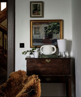 A wooden console table with ceramics and artwork