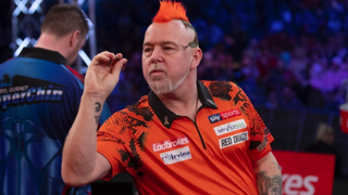 Peter "Snakebite" Wright in a red shirt takes aim while his opponent's back is turned ahead of the 2024 World Professional Darts final at Alexandra Palace in London, England.