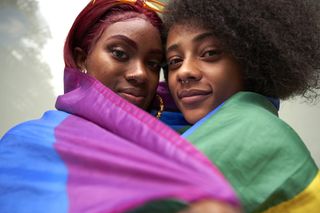 Two women wrapped in Pride Flag