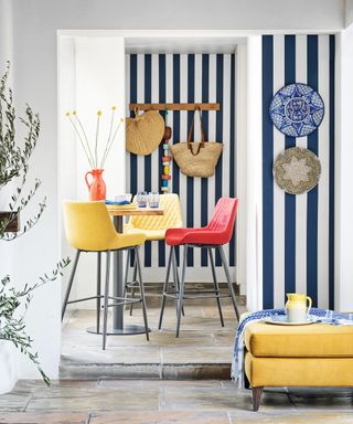 Blue and white stripe feature wall with bar table and colourful chairs in dining room