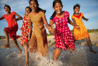 women in bright dresses holding hands