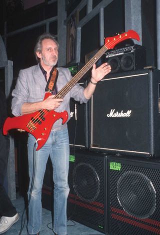 John Entwistle next to a stack of amplifiers