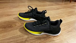 Writer Sam's UA Flow Dynamic training shoes against wooden floor