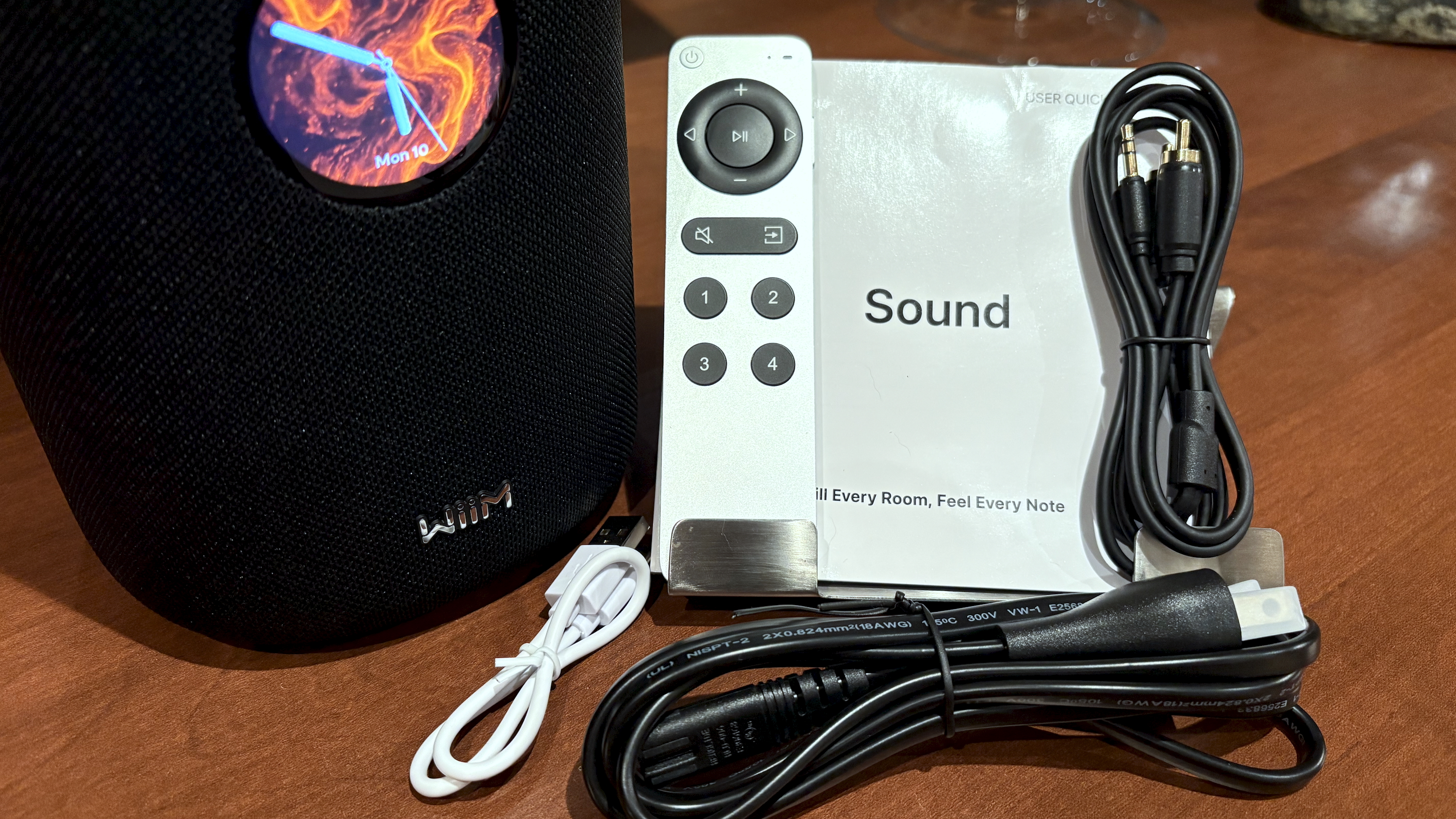 The WiiM Sound, in a home, on a varnished wooden table, showing the illuminated front panel 