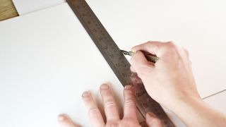 How to mount your artwork: someone measuring a piece of board with a ruler