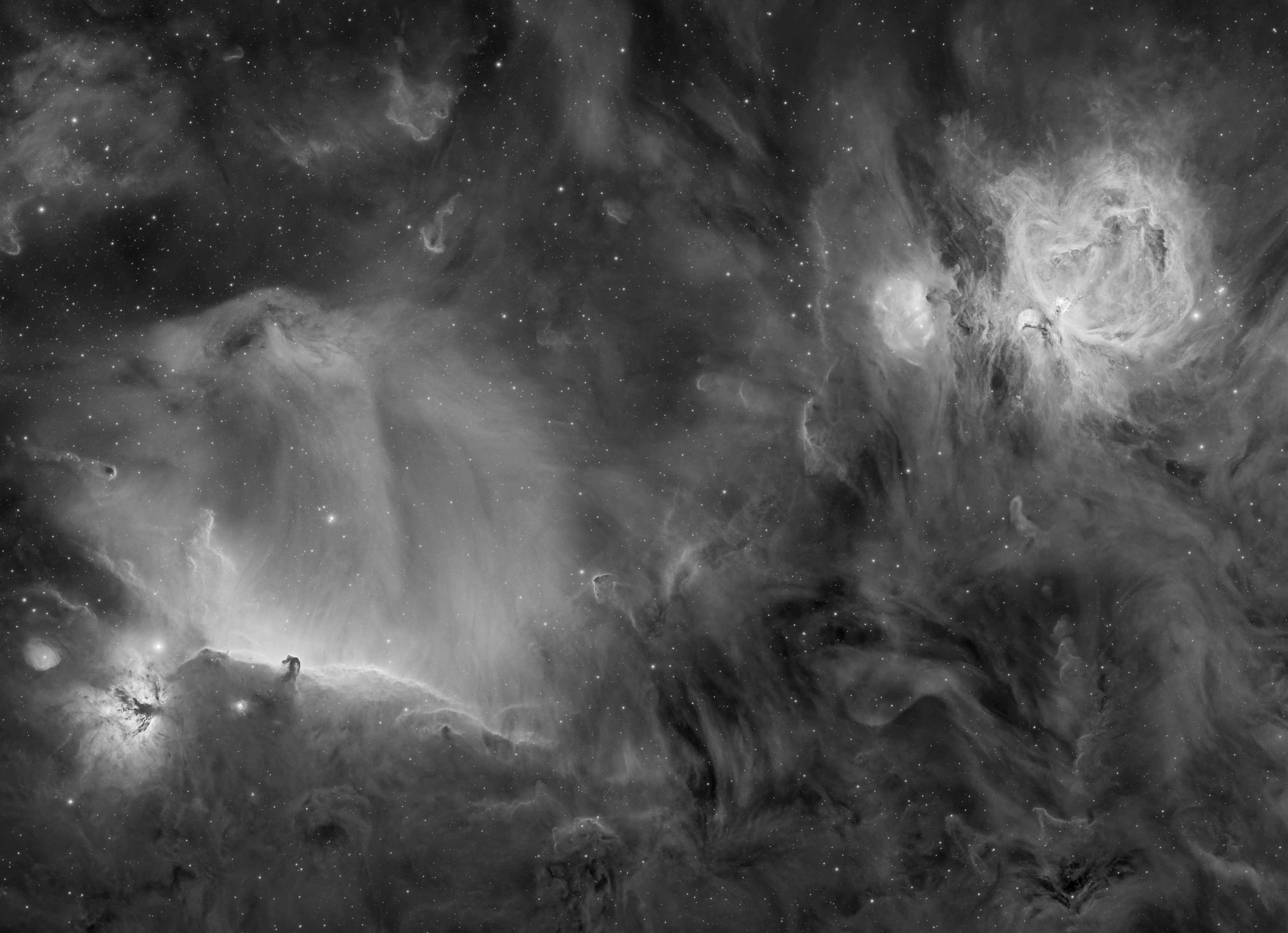 Black and white image of a nebula, showcasing swirling gas clouds and stars. A bright glow emanates from the left, creating a mysterious and ethereal atmosphere