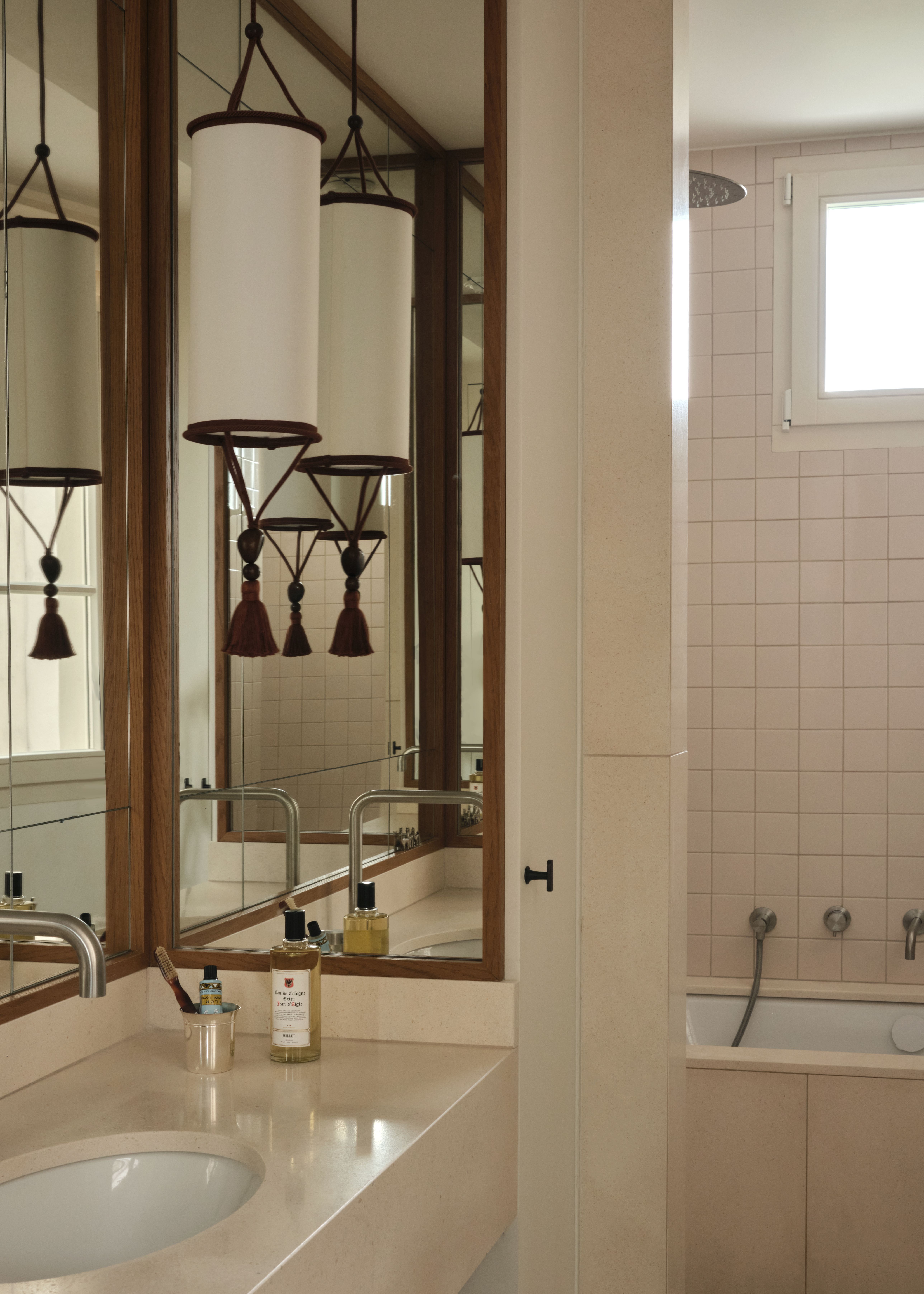 A marble-clad bathroom, with white tiling, Moroccan-inspired pendant lights, and a stone-carved basin.